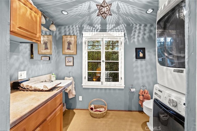 interior space with toilet, stacked washer and dryer, and vanity