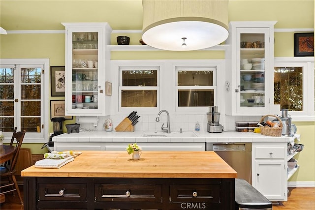 kitchen featuring dishwasher, a sink, glass insert cabinets, and white cabinetry