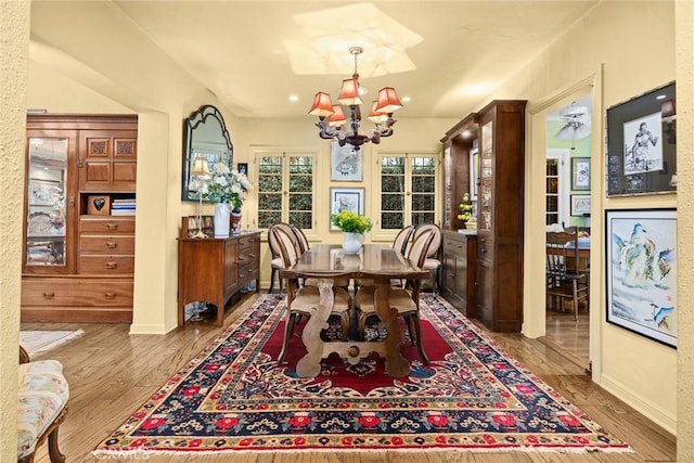 dining space featuring baseboards, wood finished floors, and a notable chandelier