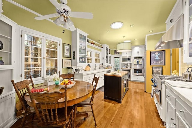 kitchen with wood counters, glass insert cabinets, a center island, stainless steel appliances, and white cabinetry