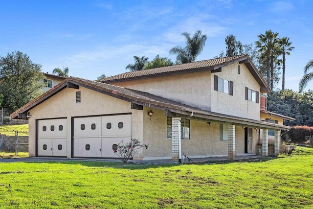 view of front of property with an attached garage, fence, a front lawn, and stucco siding