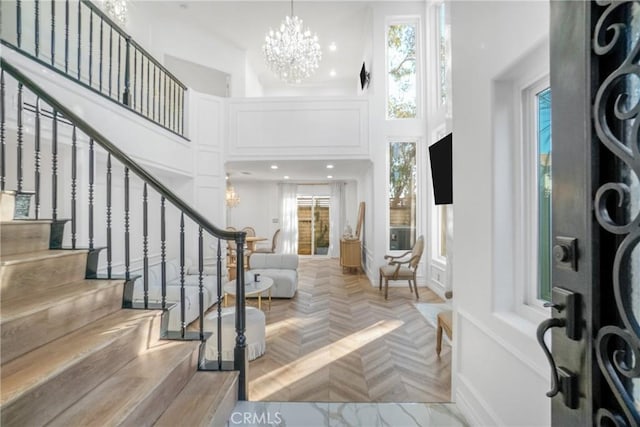 entrance foyer featuring light parquet flooring, a chandelier, and a towering ceiling