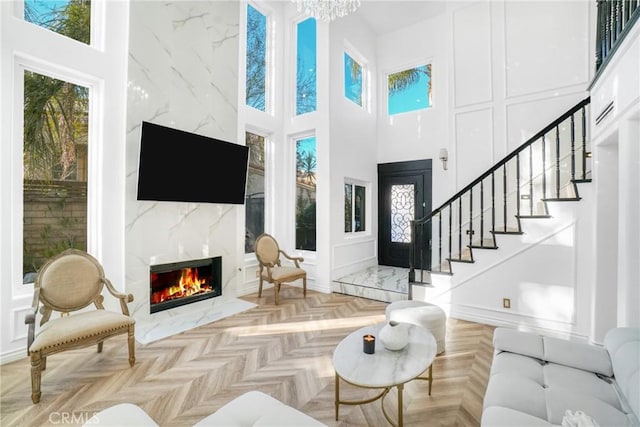 living room with a fireplace, a high ceiling, an inviting chandelier, and light parquet floors