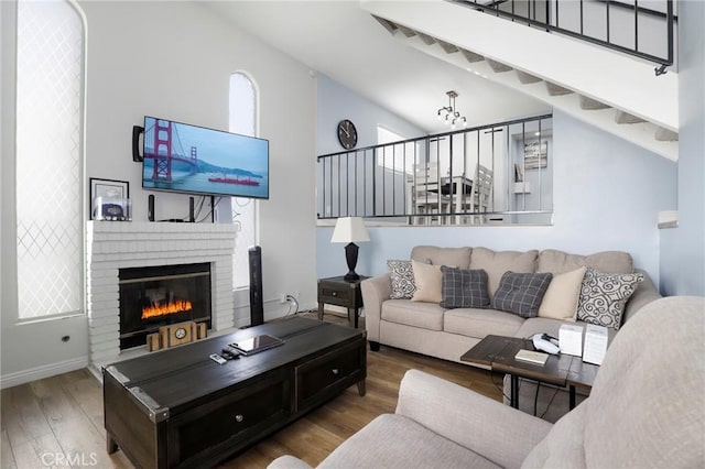 living room featuring a brick fireplace, lofted ceiling, and hardwood / wood-style floors