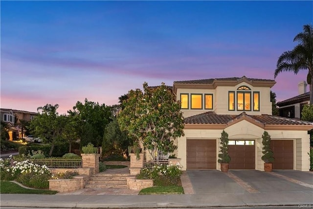 view of front facade with a tiled roof, an attached garage, driveway, and stucco siding