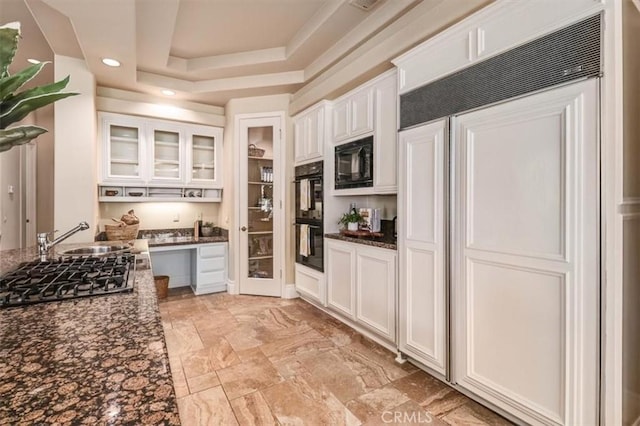 kitchen with glass insert cabinets, dark stone counters, white cabinets, a sink, and black appliances