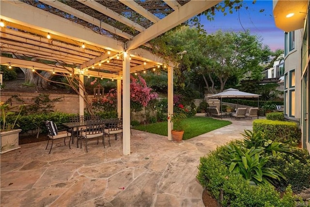 patio terrace at dusk featuring a pergola and outdoor dining space
