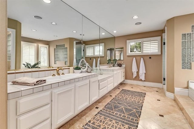 bathroom with a sink, double vanity, recessed lighting, baseboards, and a shower