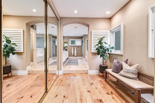 interior space with arched walkways, baseboards, recessed lighting, and light wood-style flooring