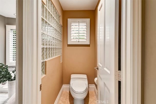bathroom with baseboards, tile patterned floors, and toilet