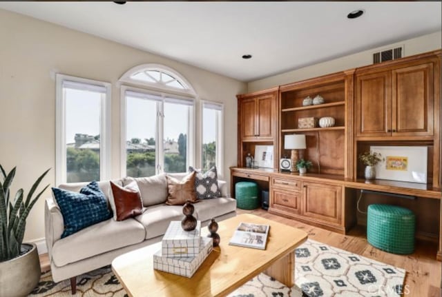 living room with visible vents, light wood-style flooring, and built in study area