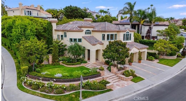 mediterranean / spanish-style house with a garage, stucco siding, a tile roof, and concrete driveway