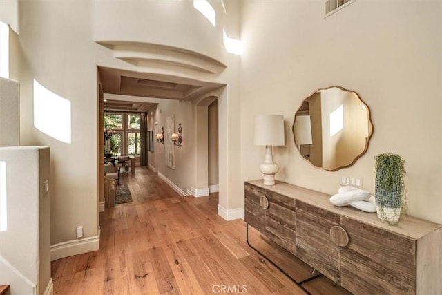 corridor featuring baseboards, light wood-style flooring, and visible vents
