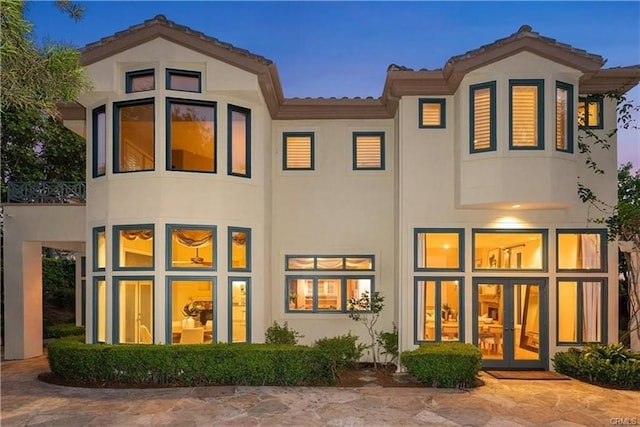 rear view of house featuring french doors, a balcony, and stucco siding