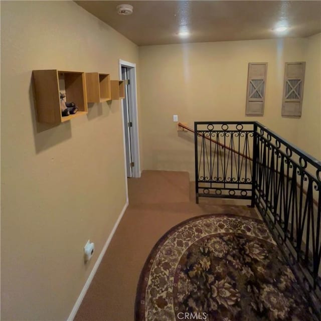 hallway with carpet floors, an upstairs landing, and baseboards