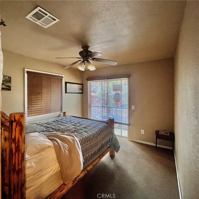 carpeted bedroom with a textured ceiling, baseboards, visible vents, and a ceiling fan