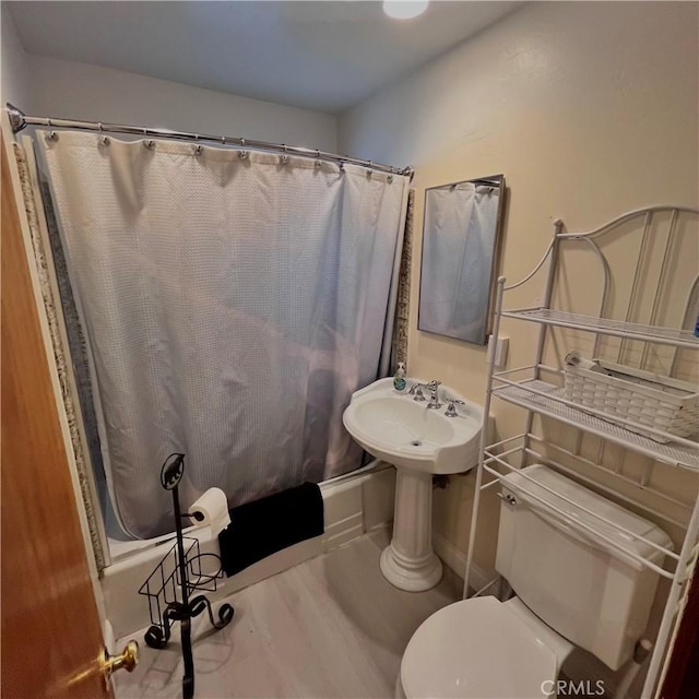 full bathroom featuring wood finished floors, toilet, and shower / bathtub combination with curtain