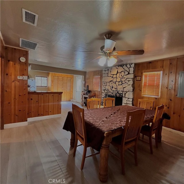 dining room featuring wood walls, a fireplace, and visible vents