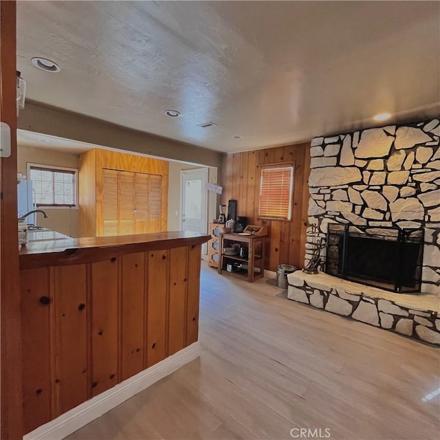 kitchen featuring wooden walls, fridge, a fireplace, and wood finished floors