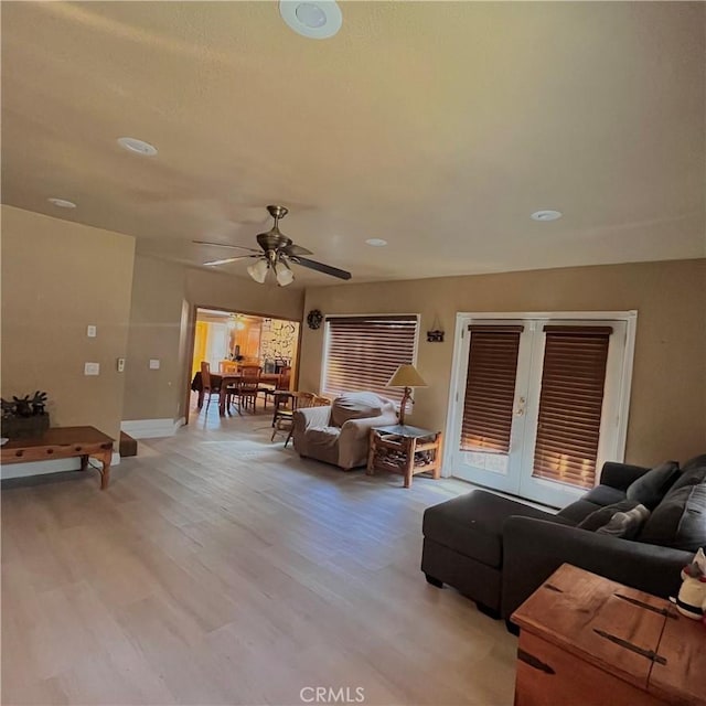 living room featuring french doors, light wood finished floors, and a ceiling fan