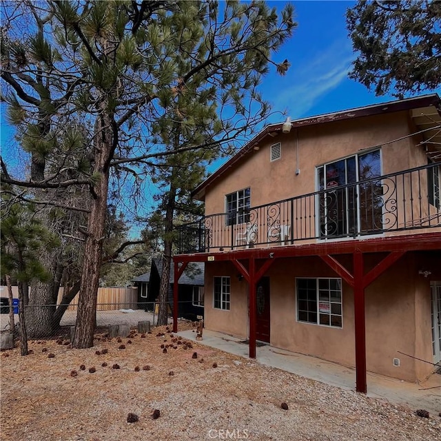 rear view of property featuring a patio area, fence, a deck, and stucco siding