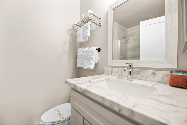 bathroom with toilet, vanity, and tiled shower