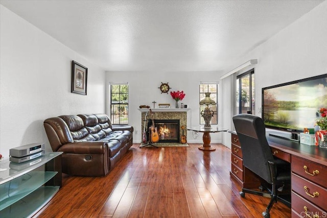 office with dark wood-style floors, a fireplace with flush hearth, and a wealth of natural light