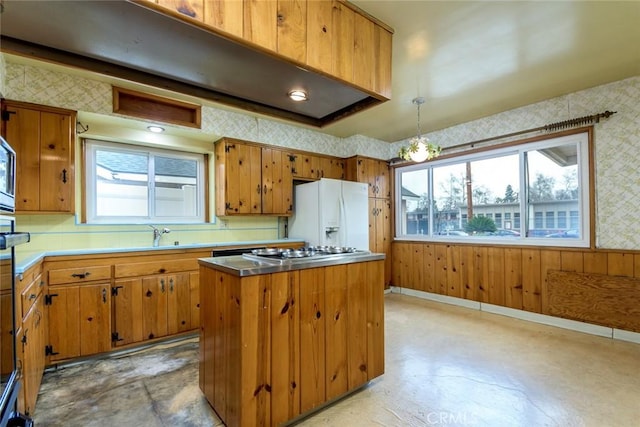 kitchen featuring a center island, white refrigerator with ice dispenser, a healthy amount of sunlight, and stainless steel gas stovetop