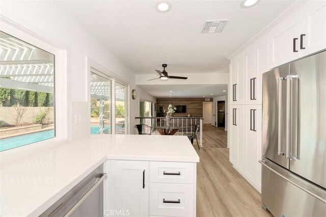 kitchen featuring visible vents, white cabinetry, open floor plan, high end fridge, and light countertops