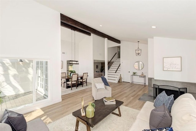 living room featuring recessed lighting, a fireplace, stairway, light wood finished floors, and beamed ceiling