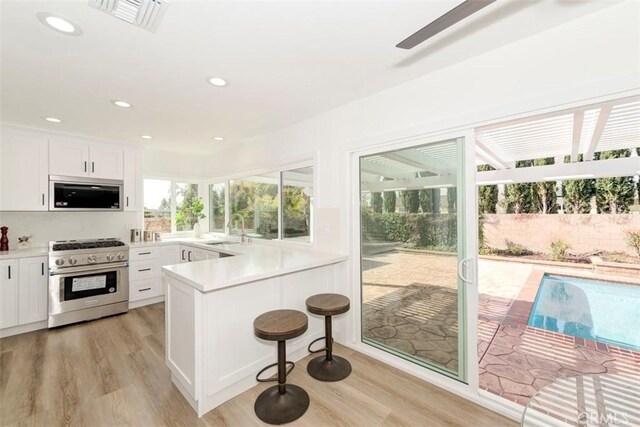 kitchen featuring stainless steel appliances, a sink, visible vents, white cabinets, and light countertops