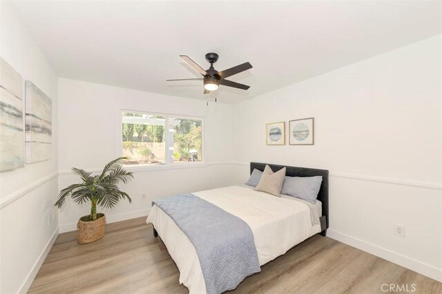 bedroom featuring ceiling fan, light wood finished floors, and baseboards