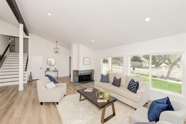 living room featuring vaulted ceiling with beams, light wood-type flooring, stairs, and recessed lighting