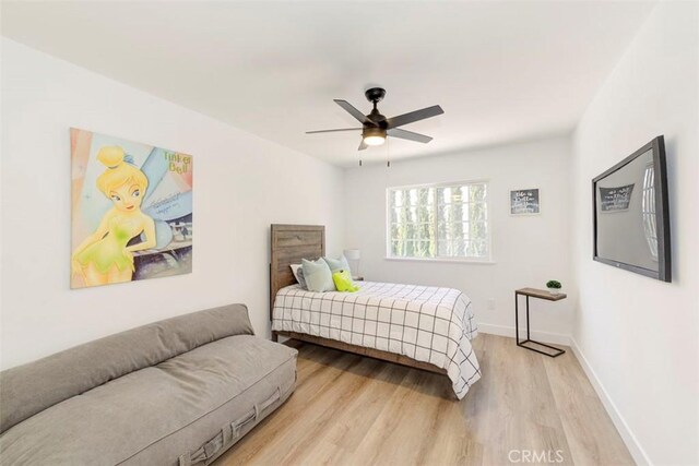 bedroom featuring a ceiling fan, baseboards, and light wood finished floors