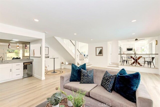 living area with light wood-type flooring, stairs, wet bar, and recessed lighting