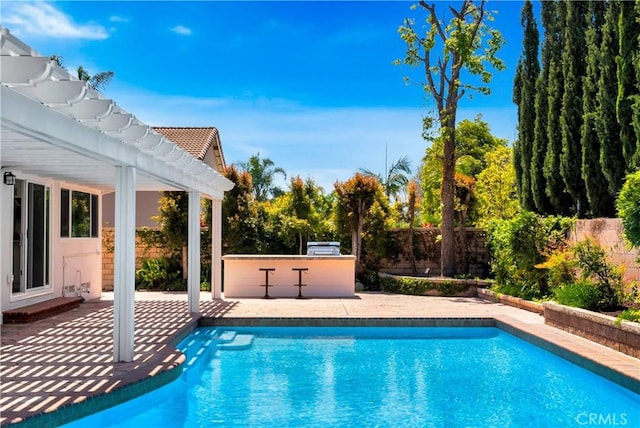 view of pool with a pergola, a fenced backyard, a patio, a fenced in pool, and an outdoor kitchen