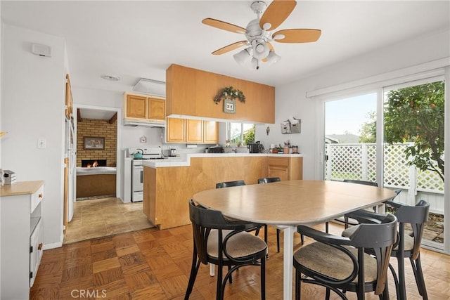 kitchen featuring white range with gas cooktop, parquet floors, kitchen peninsula, and a healthy amount of sunlight