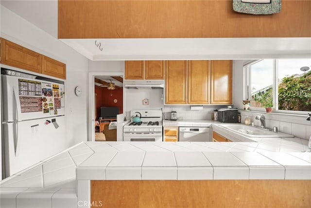 kitchen featuring tile countertops, white appliances, ceiling fan, sink, and kitchen peninsula