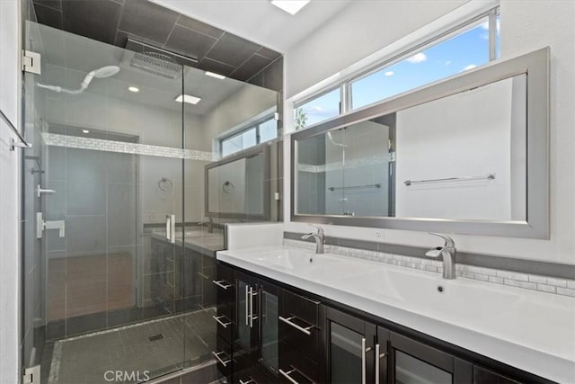 full bathroom with double vanity, a stall shower, and a sink