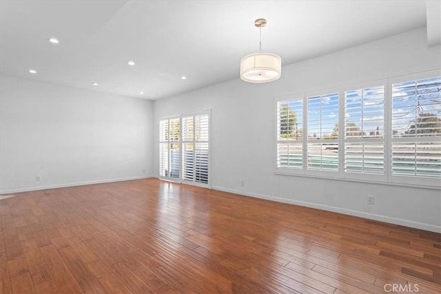 empty room featuring baseboards, wood finished floors, and recessed lighting