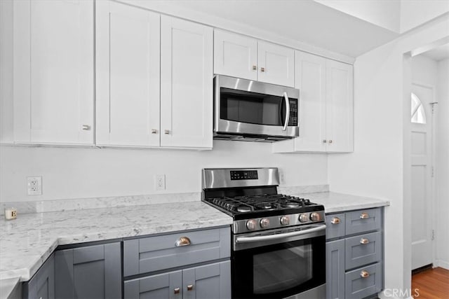 kitchen featuring white cabinetry, stainless steel appliances, light stone counters, and gray cabinetry