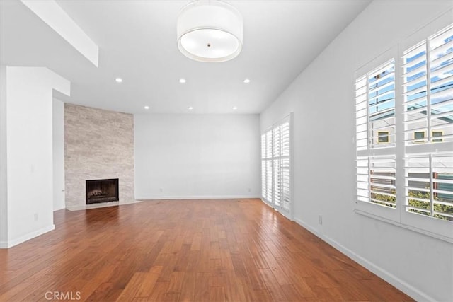 unfurnished living room with recessed lighting, baseboards, wood finished floors, and a fireplace