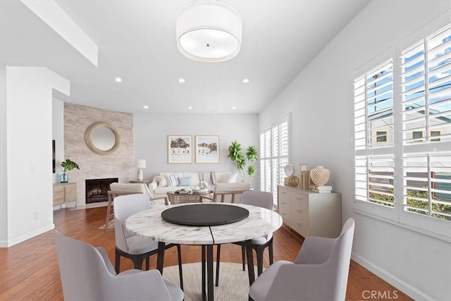 dining space featuring a fireplace, recessed lighting, wood finished floors, and baseboards