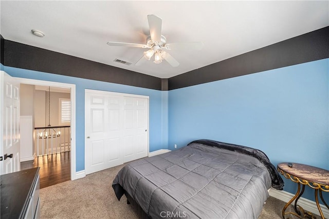 bedroom with ceiling fan with notable chandelier, carpet floors, visible vents, baseboards, and a closet