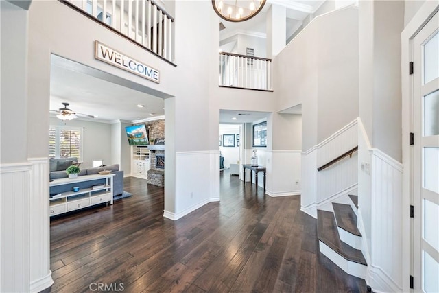 foyer entrance featuring a wainscoted wall, stairway, dark wood-type flooring, and an inviting chandelier