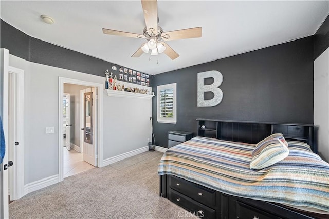 bedroom with light colored carpet, ceiling fan, baseboards, and ensuite bathroom