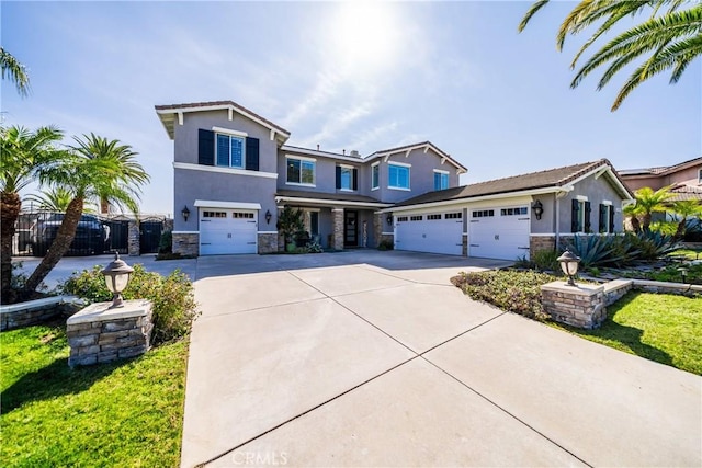 view of front of home with stone siding, concrete driveway, fence, and stucco siding