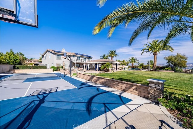 view of swimming pool with basketball hoop and a lawn