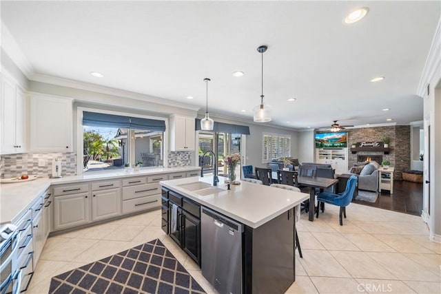 kitchen featuring light countertops, an island with sink, a sink, and white cabinetry