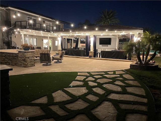 rear view of house with a balcony, stucco siding, stairway, and a patio